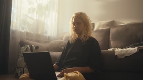 Müdes-Blondes-Mädchen-Schließt-Abrupt-Ihren-Laptop,-Nachdem-Sie-Lange-Zeit-Filme-Neben-Dem-Sofa-Zu-Hause-Geschaut-Hat