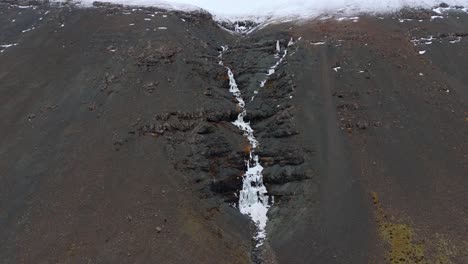 frozen skutafoss waterfall cascade in black rock mountainside, iceland