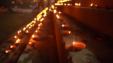 closeup of lit diya at the ghats of varanasi during dev diwali