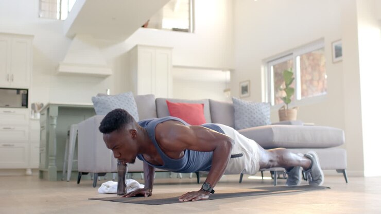 Focused african american man doing push ups in sunny living room, slow motion