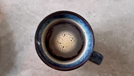 cup of black coffee in city cafe rotating foam top view