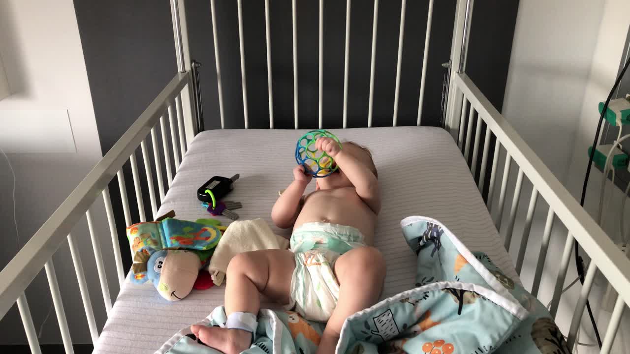 그녀의 아기 장난감을 가지고 그녀의 침대에서 노는 아기