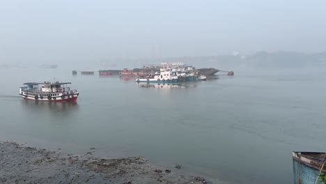 Wide-angle-shot-of-a-ferry-boat-sailing-on-Hoogly-river-and-a-boat-standing-still-at-background-during-sunset-in-Kolkata,-India