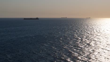 Luftaufnahme-Eines-LKW-Panoramas,-Während-Containerschiffe-Mitten-Im-Ozean-Vor-Der-Küste-Warten