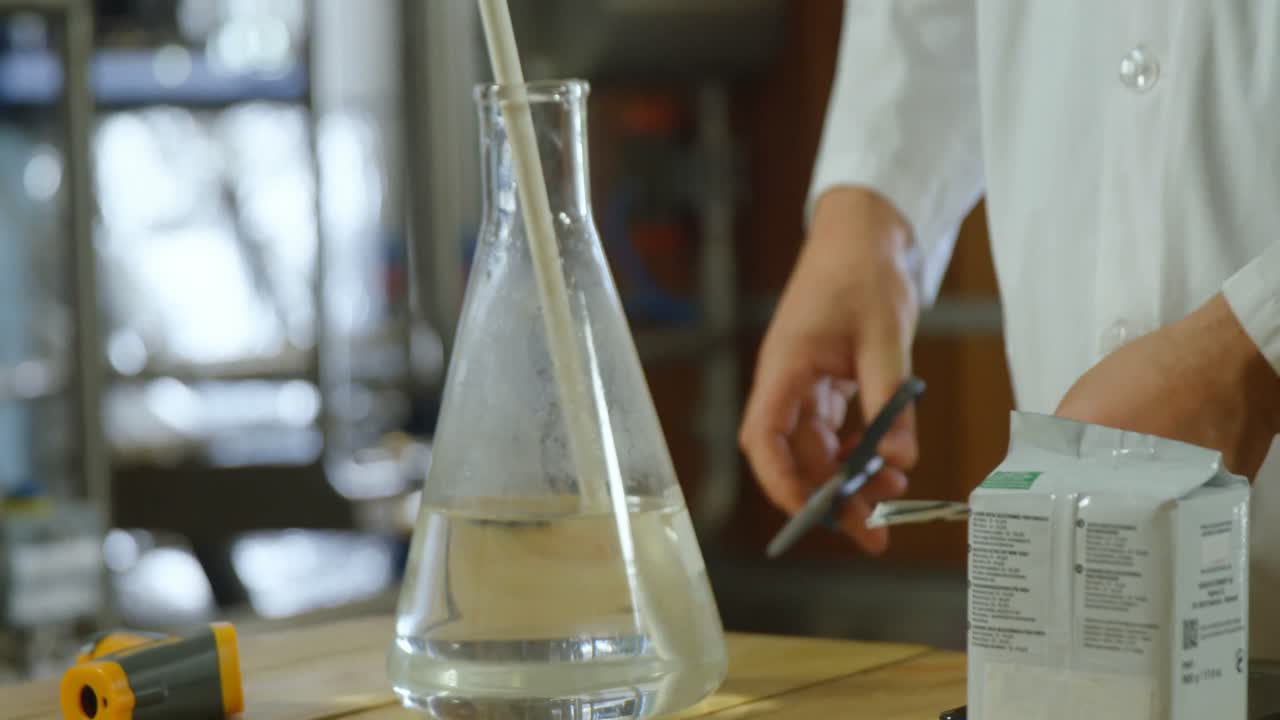 trabajador masculino examinando el licor en el frasco 4k