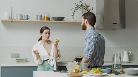 pareja feliz de pie y divirtiéndose en una cocina de estilo moderno