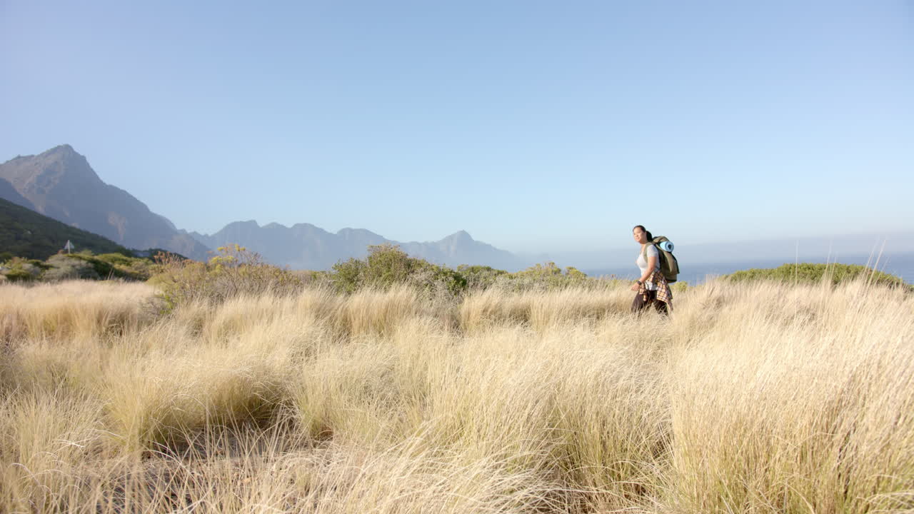Hiking through tall grass, man with backpack exploring mountain landscape, copy space