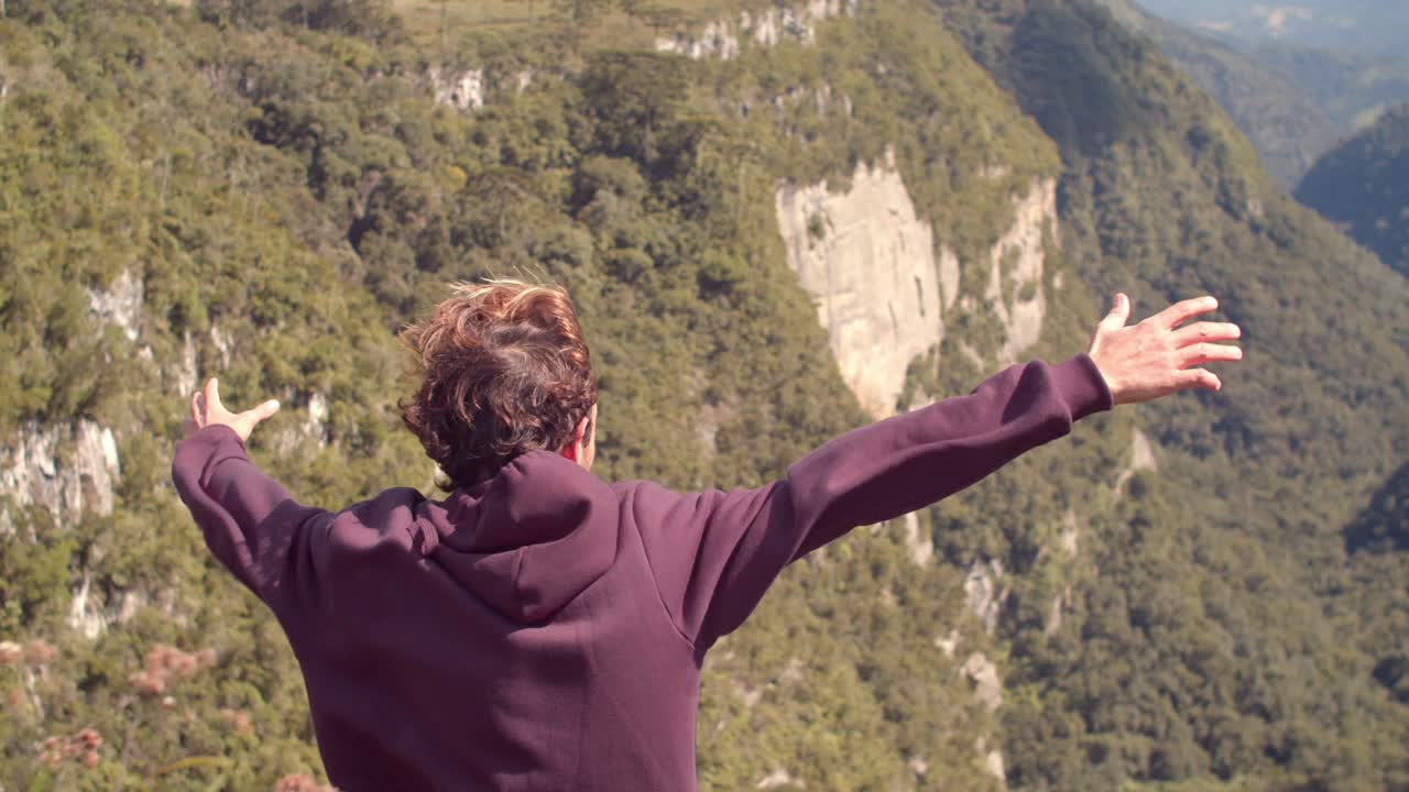 Attractive Man On Top Of Mountain Enjoying The Strong Wind And View Of Fortaleza Canyon In Serra Geral National Park, Brazil. high-angle shot