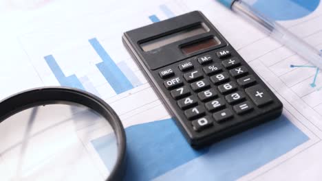 business documents with calculator, graphs, and magnifying glass