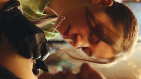 female tattooist in gloves doing handpoke tattoo with needle