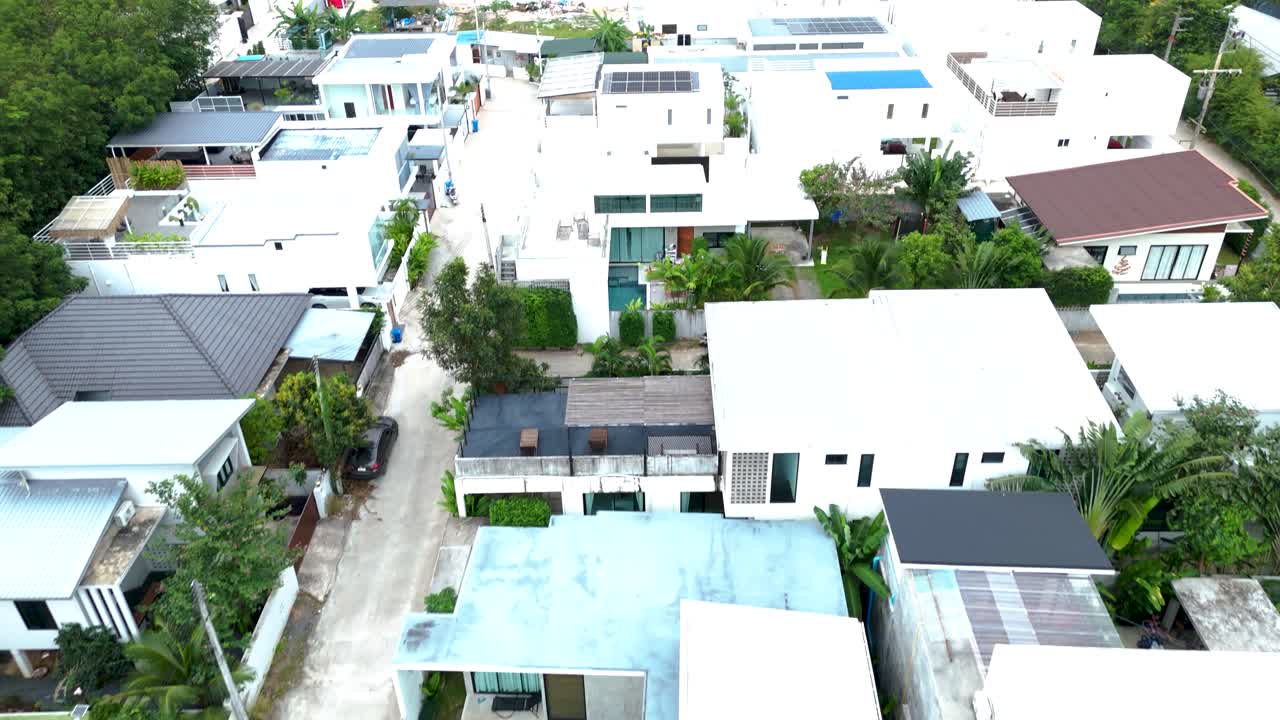 Aerial revealing shot of luxury mansions beside a palm tree forest in Koh Samui