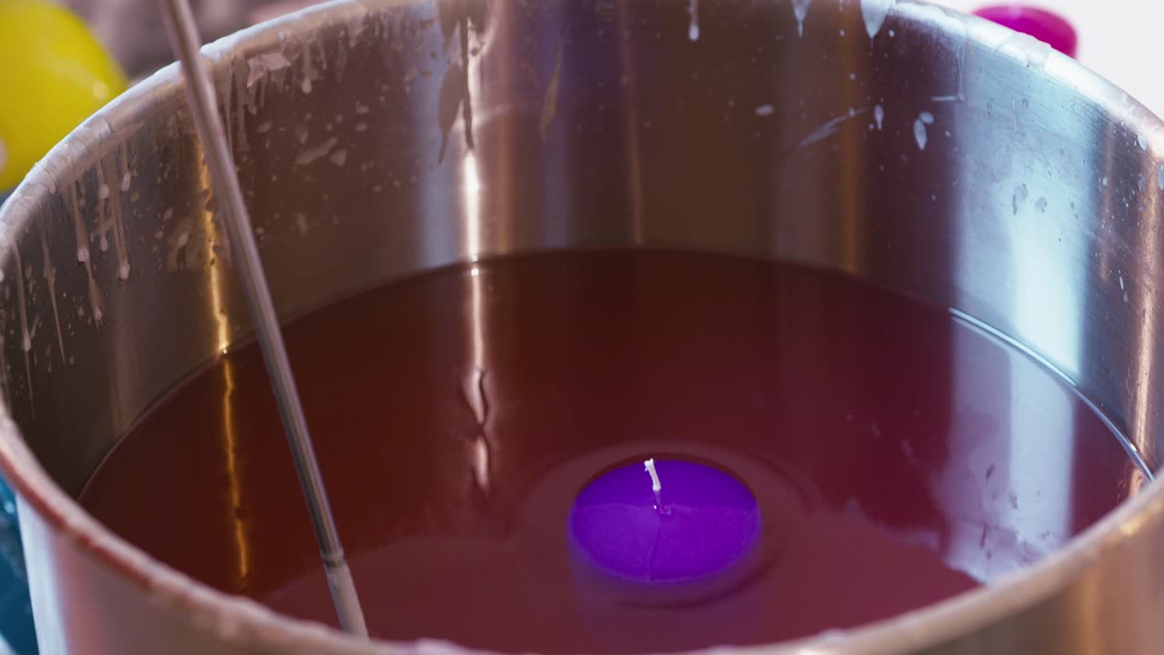 Dipping a purple candle in liquid wax