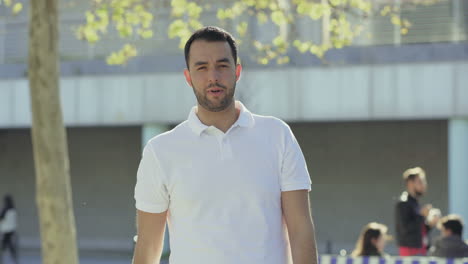 Smiling-young-man-standing-on-street-and-gesturing.