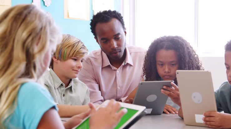 Teacher helping kids using tablet in elementary school class