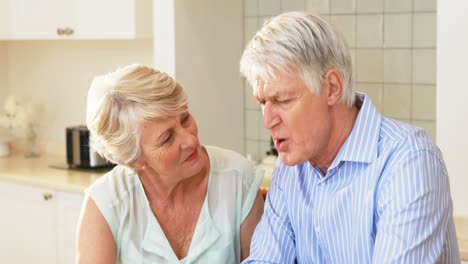 Senior-couple-using-laptop-in-kitchen