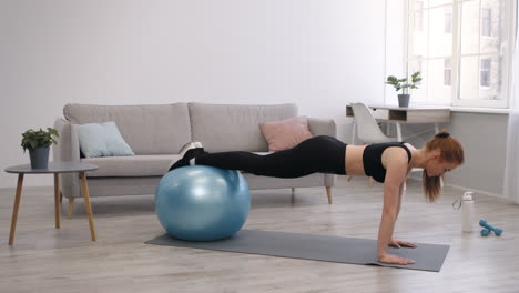 woman doing plank exercise with exercise ball at home