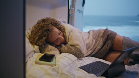 woman sleeping camper van bed with laptop close up. attractive lady relaxing