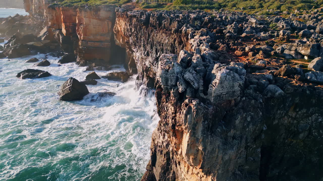 High rough coastal rock over powerful sea at sunny day. Drone volcanic cliffs