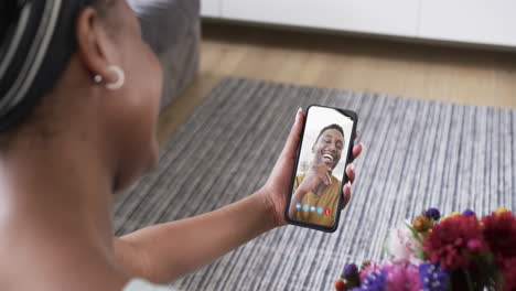 mujer afroamericana sosteniendo un teléfono inteligente con un hombre afroamericano en la pantalla