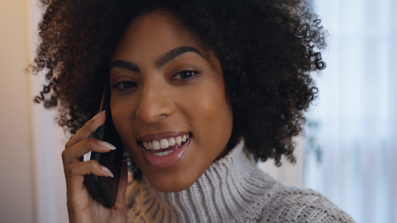 Excited lady gossiping cellphone home closeup. African woman ending conversation