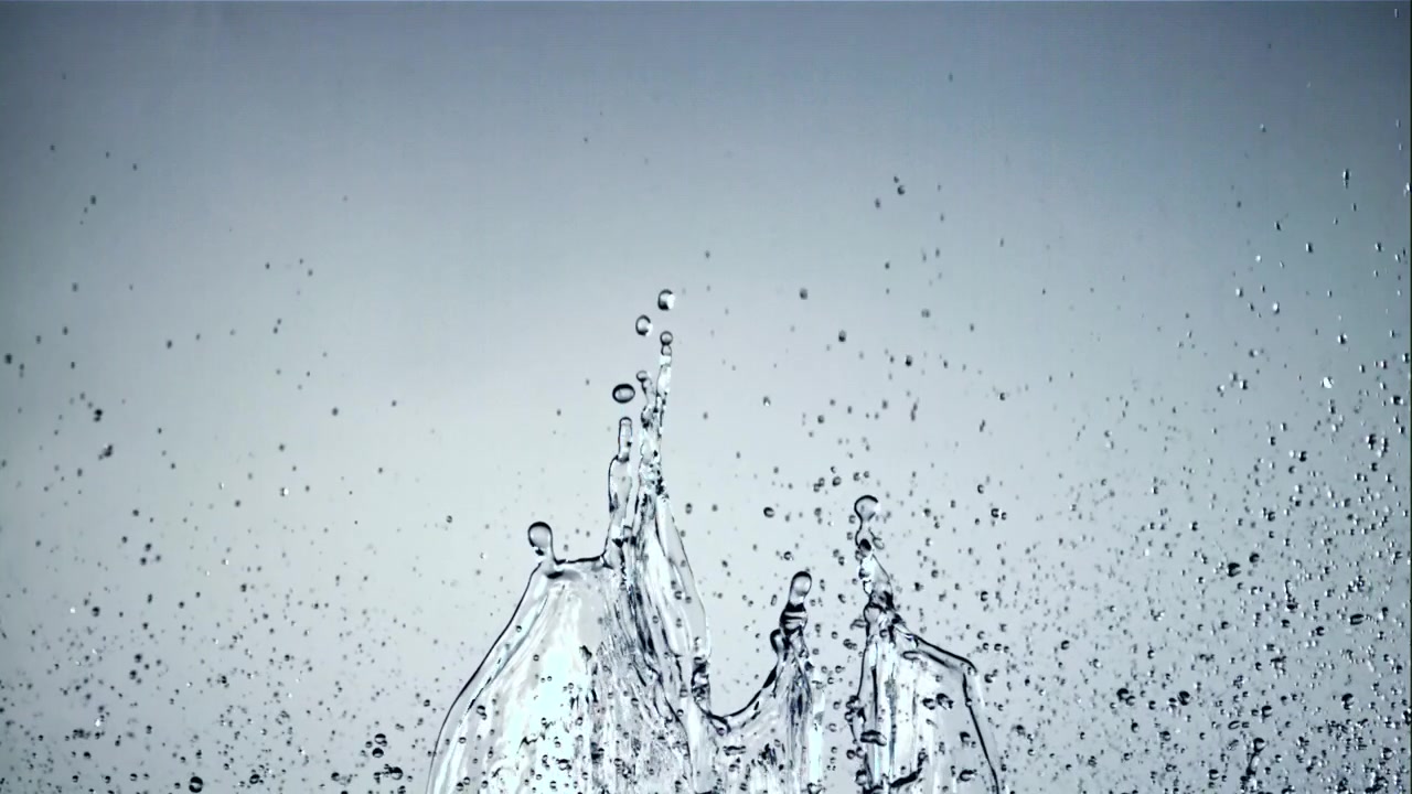 Dynamischer Wasserspritzer und Tropfen vor hellem Hintergrund
