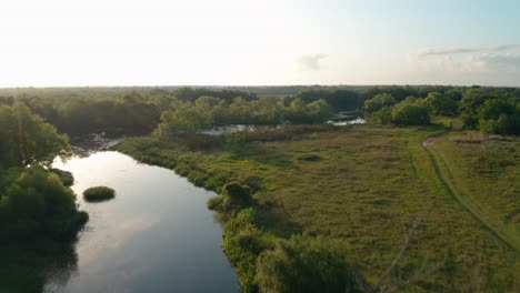 Beautiful-river-at-sunrise-on-private-Texas-hunting-ranch,-aerial-flyover-during-golden-hour-in-4k