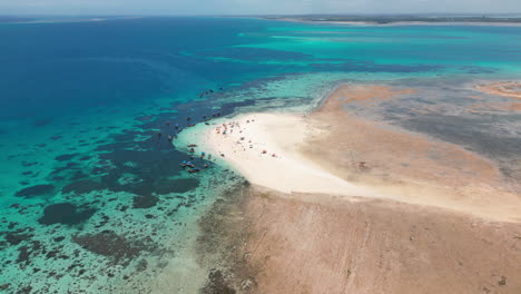 tropical beach peninsula with clear turquoise waters and crowd