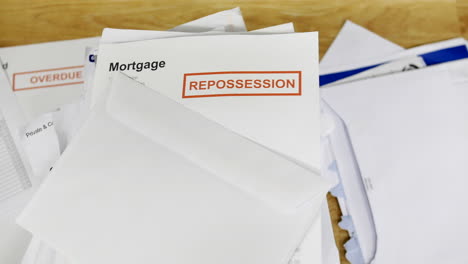 a stack of bills and debts with a mortgage repossession notice letter