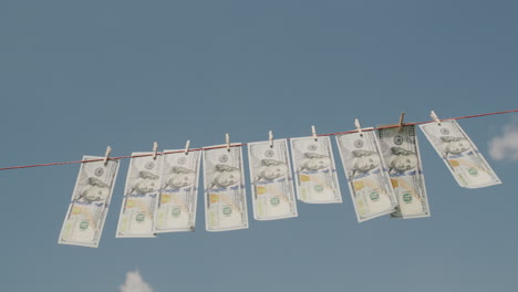 Dollar-banknotes-dry-on-a-clothesline.-Money-laundering-concept.-Low-angle-shot