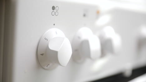 close-up of young male hand turning control knob for plate on stove