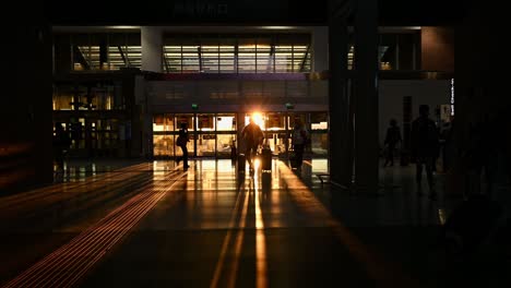 silhouette of some tourists walking inside an airport terminal during a stunning sunset. travel concept during the covid-19 pandemic.