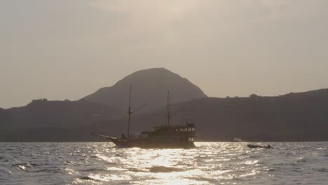 yate navega por las aguas cerca de la isla de komodo, con un telón de fondo de una pequeña isla montañosa