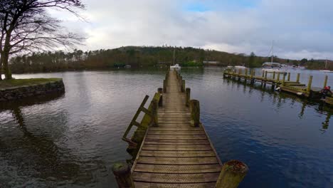 lake windermere in the english lake district, with its iconic wooden jetty, historic stone-built buildings, and moody grey skies