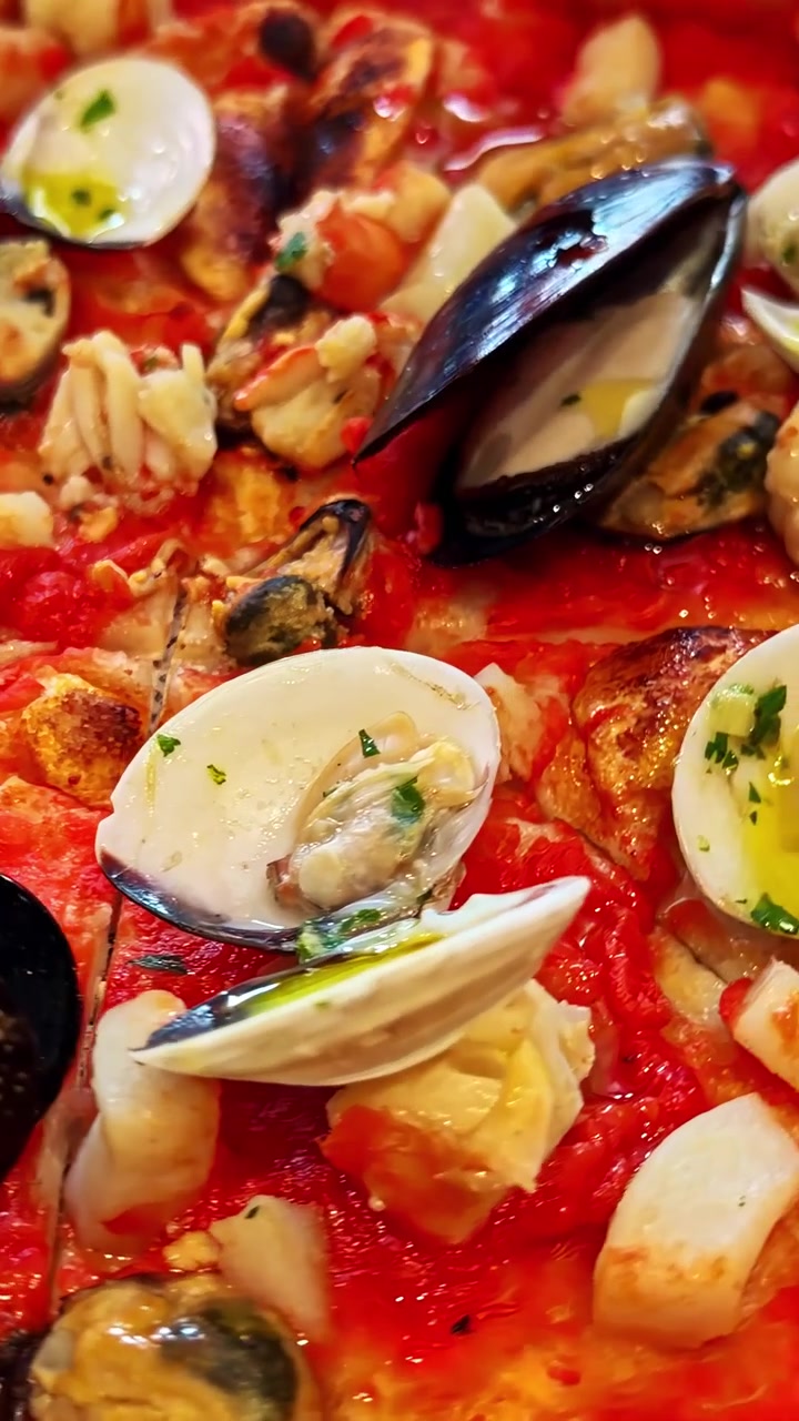 Primo piano di pizza ai frutti di mare con vari frutti di mare, ricca base di pomodoro e formaggio fuso.