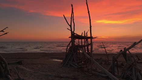 Driftwood-tipis-at-sandy-beach-during-sunset