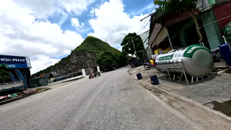 pov drive through a vietnamese street with mountains, scooter, and urban scenery