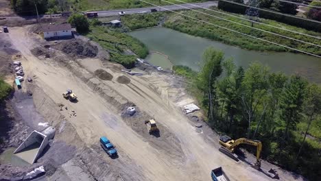 construction machines work on a holding pond roller and bulldozer sewer pipes aerial establishing shot