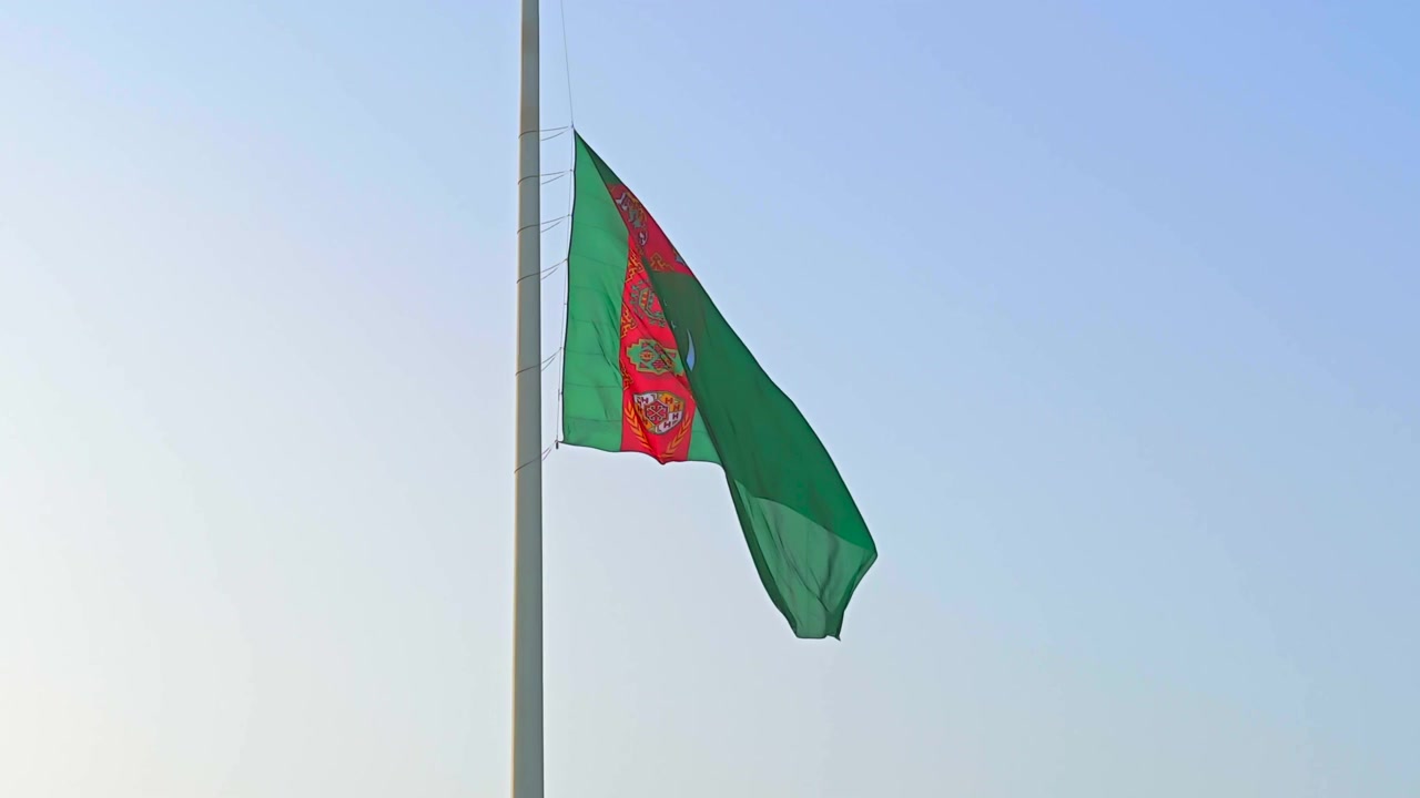 Bandera de Turkmenistán ondeando contra un cielo azul claro