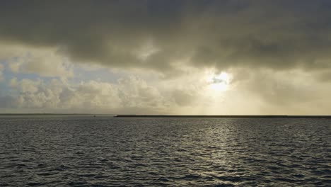 From-the-perspective-of-a-watercraft,-an-expansive-panoramic-scene-materializes-an-image-of-colossal-sunset-clouds-illuminated-by-divine-rays