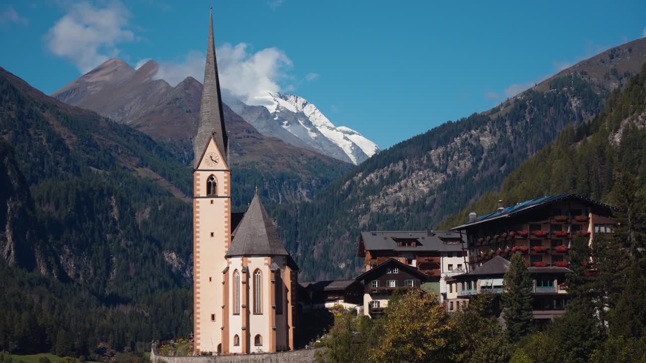 Vista fissa della chiesa di Heiligenblut e chalet alpini con montagne sullo sfondo