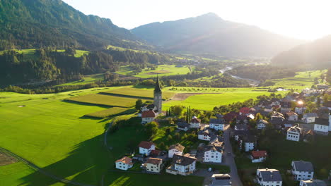 drone flies towards church in sagogn swiss with beautiful autumn colours