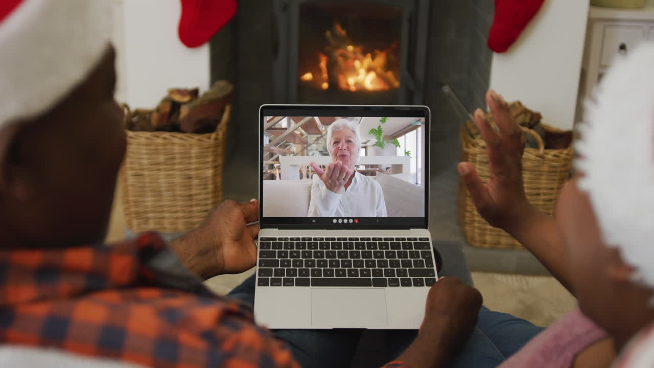 pareja afroamericana con sombreros de santa usando una computadora portátil para una videollamada de navidad con una mujer en la pantalla