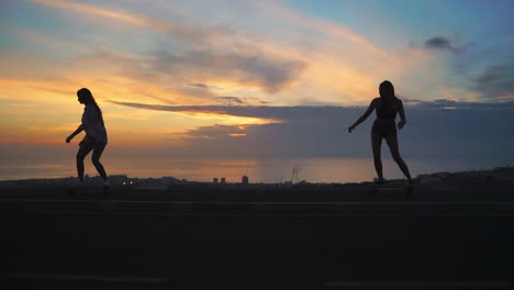 amidst a backdrop of mountains and a captivating sky, two girls enjoy slow-motion skateboarding on a road at sunset. both are wearing shorts