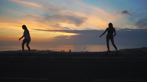 en medio de un telón de fondo de montañas y un cielo cautivador, dos niñas disfrutan de skateboarding en cámara lenta en una carretera al atardecer. ambas llevan pantalones cortos