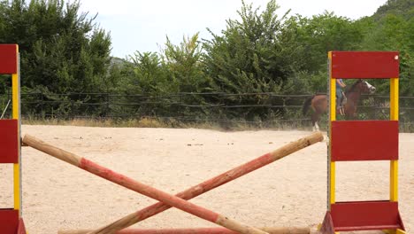 Hurdle in an equestrian show jumping track with a woman galloping in the background during training