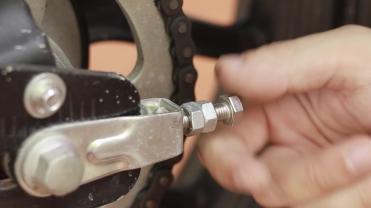 Close up to a hand tightening a nut and bolt screw in the process of tuning a motorcycle part