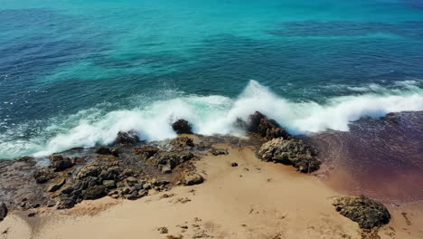 aerial view of waves crashing on a sandy and rocky beach