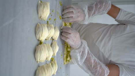 the turkish pastry chef prepares oyster baklava and fills it with cream and pistachios , slow motion video, vertical video