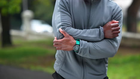 hombre en traje de entrenamiento gris, brazos cruzados
