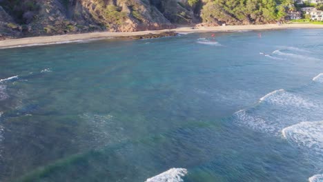 Drone-footage-of-white-capped-waves-rolling-onto-the-beach-on-Oahu-Hawaii-with-volcanic-rock-formations-lining-the-sandy-shore